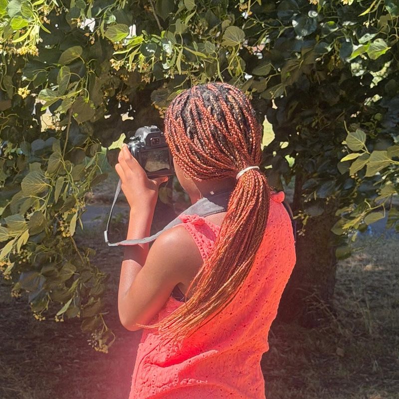Young photographer taking a shot under a tree